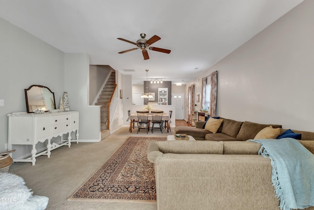 carpeted living room with stairs, ceiling fan, and baseboards