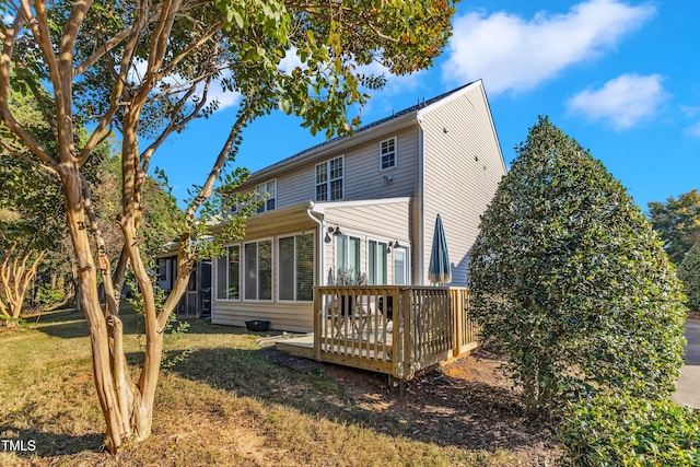 rear view of house with a deck, a lawn, and a sunroom