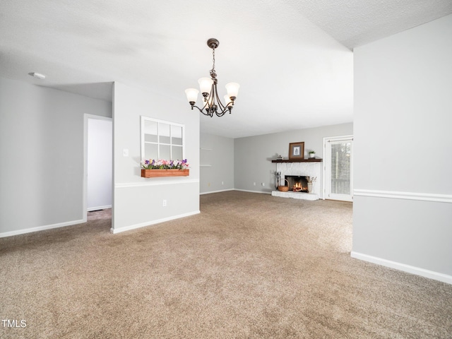 unfurnished living room with a warm lit fireplace, a textured ceiling, a notable chandelier, carpet floors, and baseboards