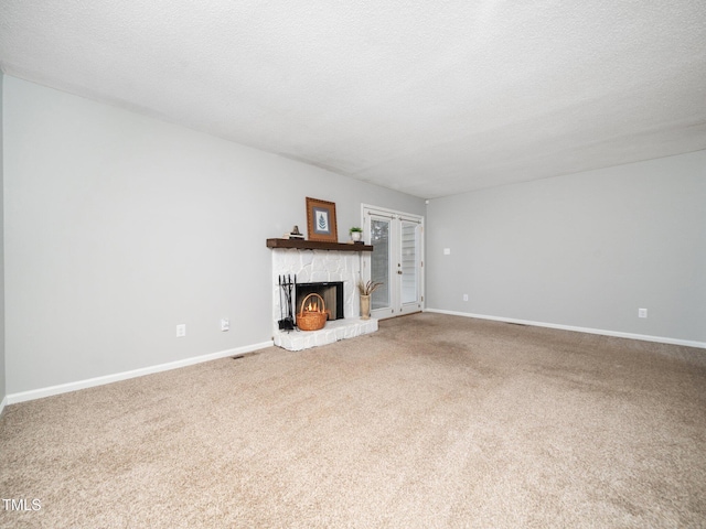 unfurnished living room featuring carpet flooring, a fireplace, a textured ceiling, and baseboards