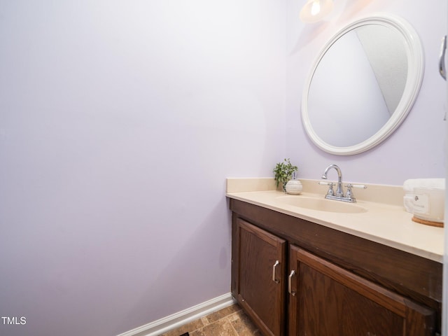 bathroom featuring stone finish flooring, baseboards, and vanity