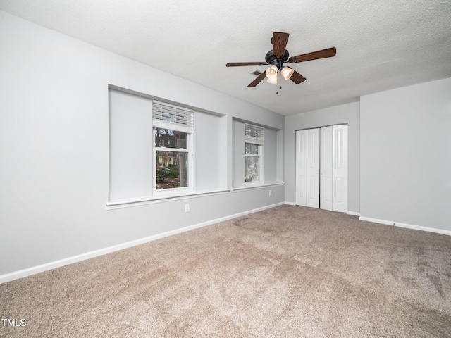 unfurnished bedroom featuring a textured ceiling, ceiling fan, carpet floors, baseboards, and a closet