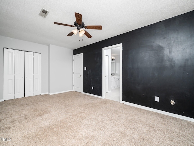 unfurnished bedroom with light carpet, a textured ceiling, a closet, and visible vents