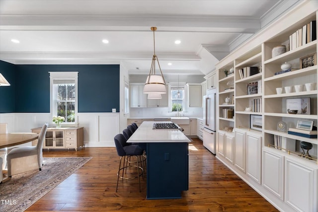 kitchen featuring a kitchen island, a breakfast bar, a wainscoted wall, and dark wood finished floors