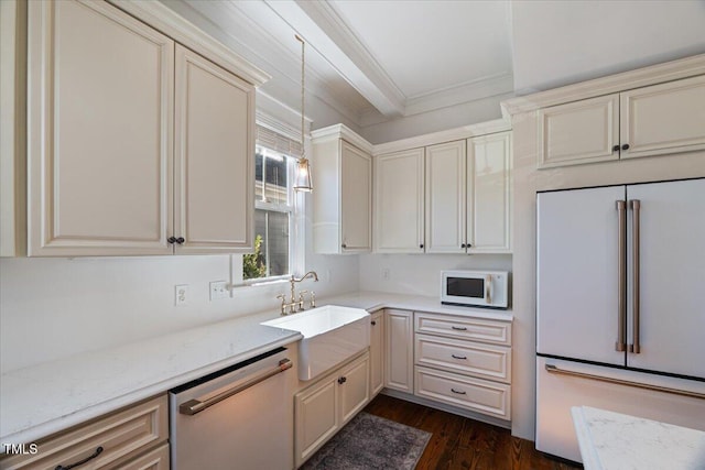 kitchen featuring dishwashing machine, white microwave, high end fridge, cream cabinets, and a sink