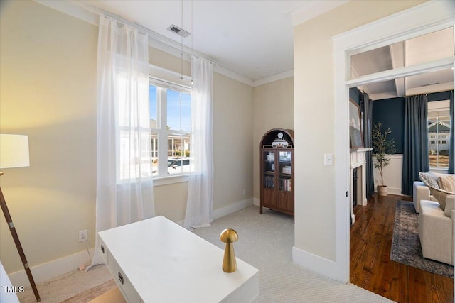 office area with visible vents, baseboards, ornamental molding, wood finished floors, and a fireplace