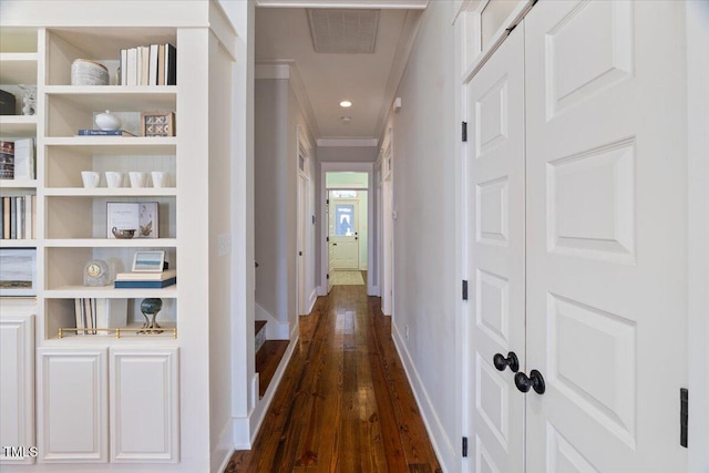 corridor featuring dark wood finished floors, recessed lighting, visible vents, ornamental molding, and baseboards