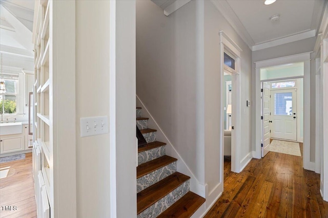 interior space featuring wood-type flooring, crown molding, and baseboards