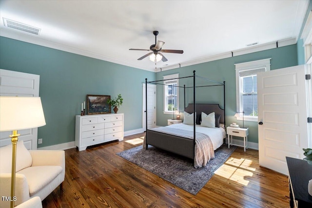 bedroom with ornamental molding, wood finished floors, visible vents, and baseboards