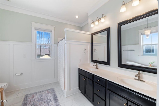 full bath featuring double vanity, a sink, and wainscoting