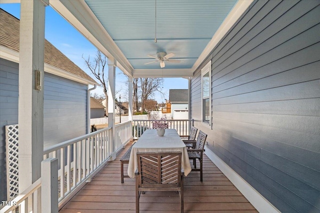 wooden terrace with outdoor dining area and a ceiling fan