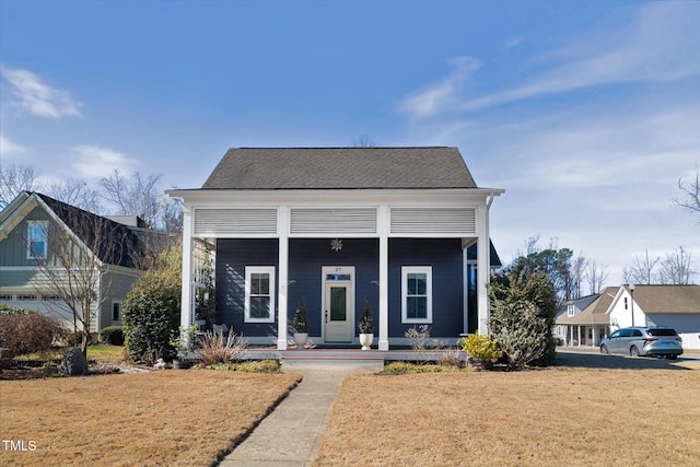 bungalow-style house featuring covered porch, a shingled roof, and a front lawn