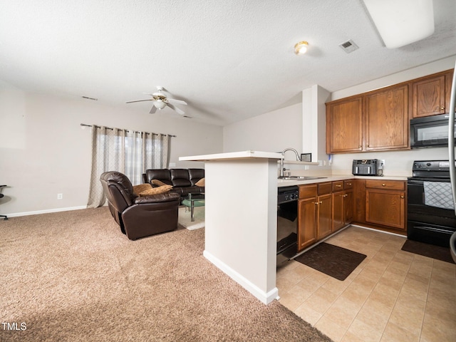 kitchen with a peninsula, a sink, open floor plan, brown cabinets, and black appliances