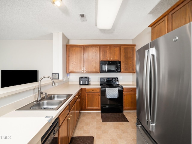 kitchen featuring black appliances, visible vents, brown cabinets, and a sink