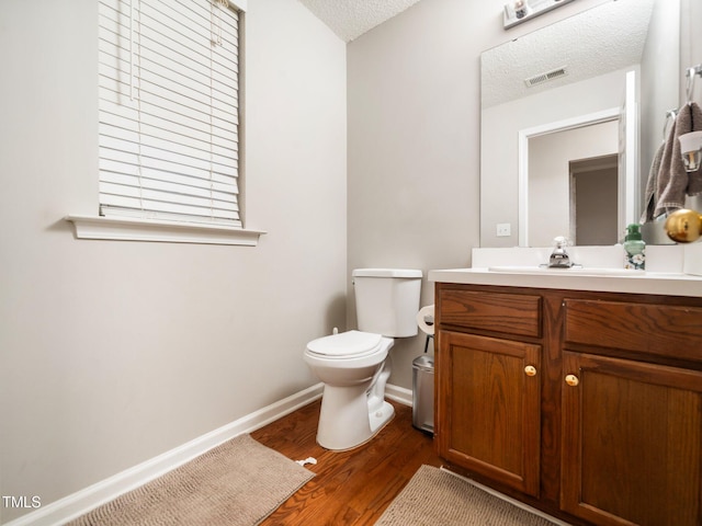 bathroom with visible vents, toilet, wood finished floors, a textured ceiling, and vanity