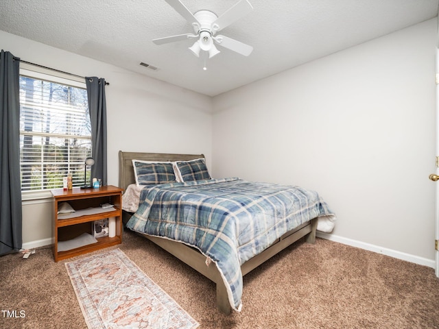 carpeted bedroom featuring baseboards, visible vents, ceiling fan, and a textured ceiling