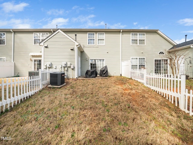 back of property with a fenced backyard, a lawn, and central AC