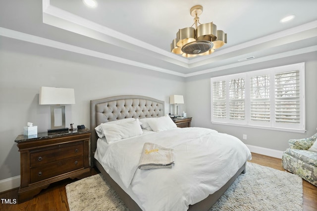 bedroom with a tray ceiling, a notable chandelier, and dark wood finished floors