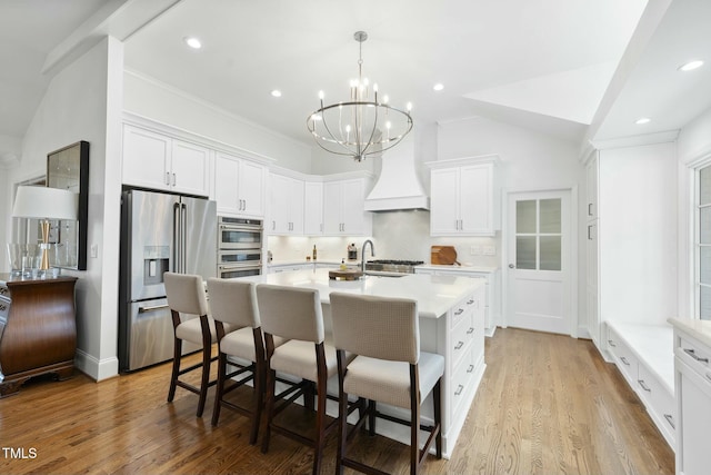 kitchen with backsplash, premium range hood, a breakfast bar area, light countertops, and appliances with stainless steel finishes