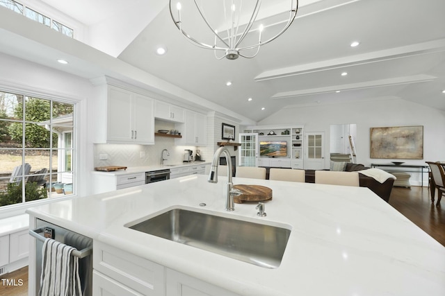 kitchen featuring dark wood-type flooring, open floor plan, lofted ceiling with beams, white cabinets, and a sink