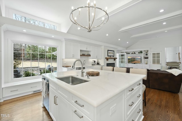 kitchen featuring a sink, stainless steel dishwasher, lofted ceiling with beams, and open floor plan