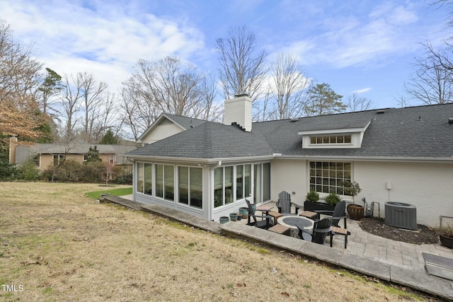 rear view of house with a patio, a yard, a sunroom, a chimney, and a shingled roof