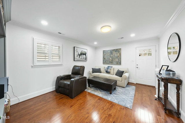 living room with hardwood / wood-style floors, baseboards, visible vents, and ornamental molding