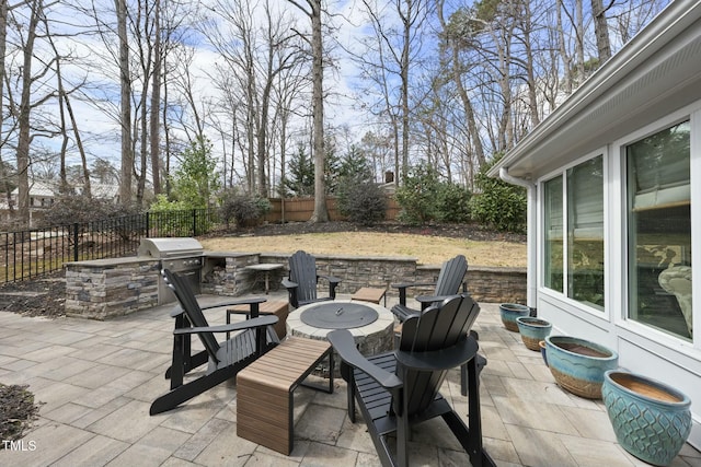 view of patio with area for grilling, a grill, a fenced backyard, and an outdoor fire pit