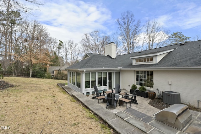 rear view of house with a patio, a lawn, a shingled roof, and a sunroom