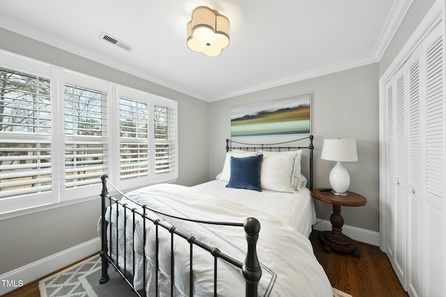 bedroom with visible vents, ornamental molding, wood finished floors, a closet, and baseboards