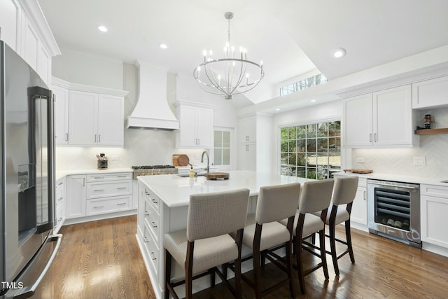 kitchen featuring dark wood-style floors, custom exhaust hood, a sink, wine cooler, and appliances with stainless steel finishes