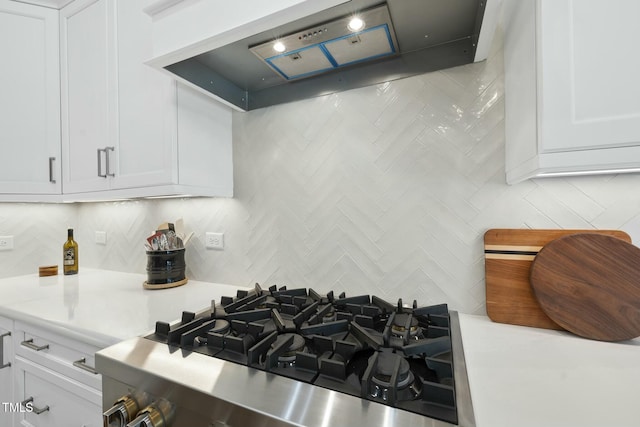 kitchen featuring stainless steel gas stove, white cabinetry, light countertops, and premium range hood