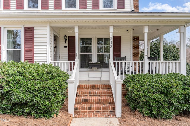 property entrance featuring a porch and brick siding