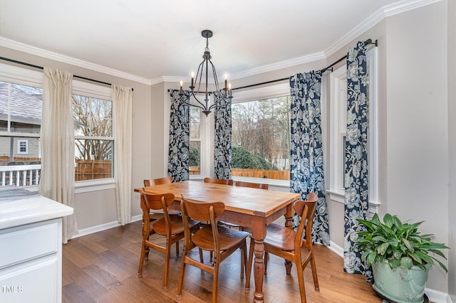 dining space with baseboards, a chandelier, wood finished floors, and crown molding