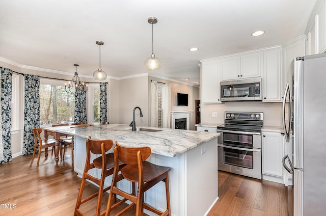 kitchen with stainless steel appliances, white cabinetry, a sink, and wood finished floors