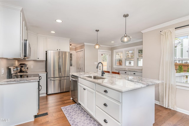 kitchen featuring stainless steel appliances, a sink, light wood-style flooring, and white cabinets