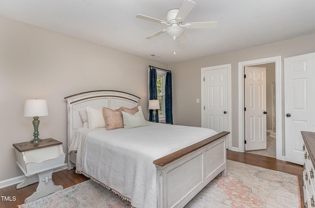 bedroom featuring ceiling fan, wood finished floors, visible vents, and baseboards