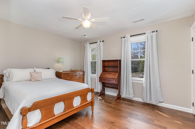 bedroom with a ceiling fan, multiple windows, baseboards, and wood finished floors