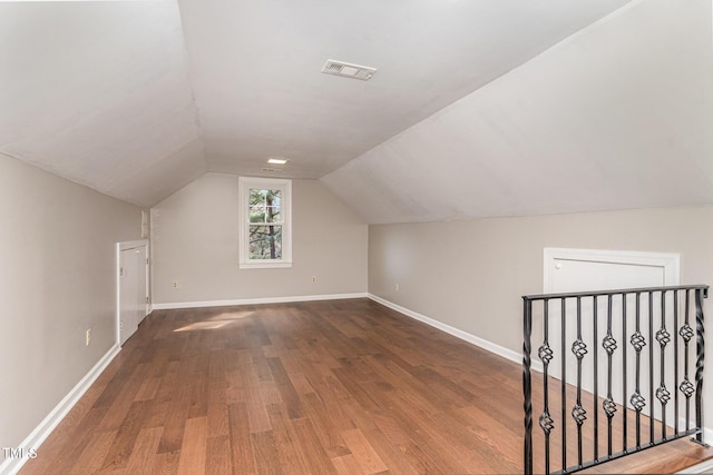 bonus room featuring visible vents, vaulted ceiling, baseboards, and wood finished floors