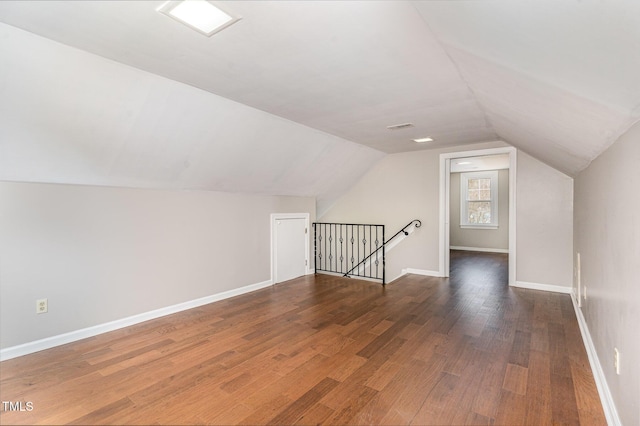 additional living space featuring baseboards, visible vents, vaulted ceiling, and wood finished floors