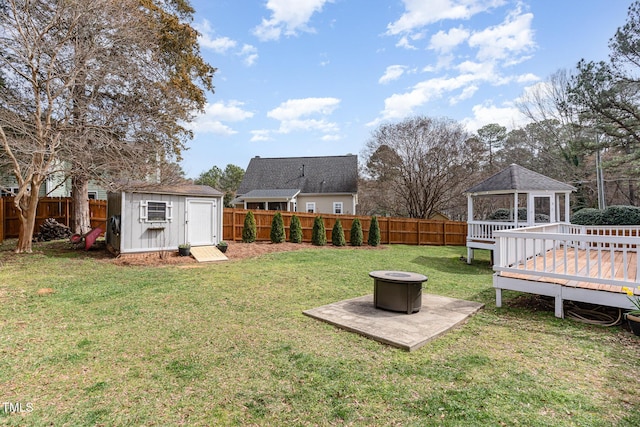 view of yard with an outdoor fire pit, a fenced backyard, an outdoor structure, and a storage unit