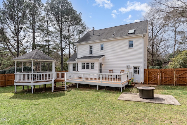 back of house featuring a lawn, a gazebo, an outdoor fire pit, a gate, and a fenced backyard