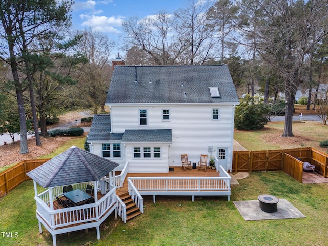 rear view of property featuring a gazebo, an outdoor fire pit, a lawn, and roof with shingles