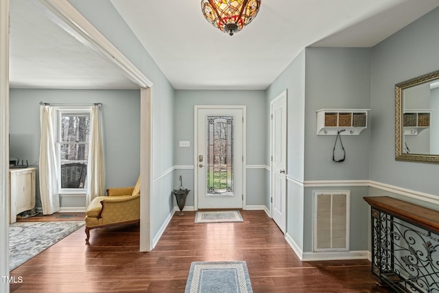 foyer featuring a wall unit AC, baseboards, visible vents, and wood finished floors