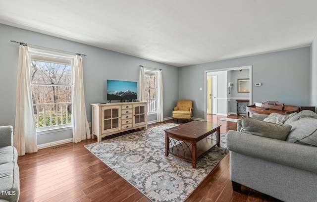 living room featuring visible vents, baseboards, and wood finished floors