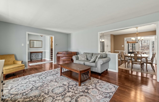 living room with a chandelier, a fireplace, baseboards, and hardwood / wood-style flooring