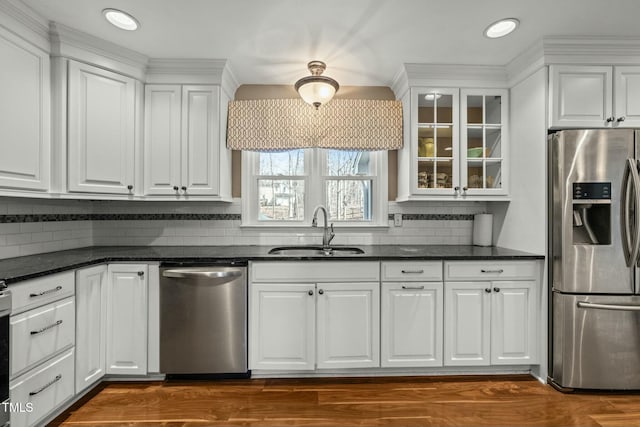 kitchen featuring stainless steel appliances, glass insert cabinets, a sink, and white cabinetry