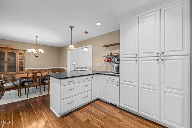 kitchen featuring a chandelier, a peninsula, dark wood-style flooring, white cabinets, and hanging light fixtures