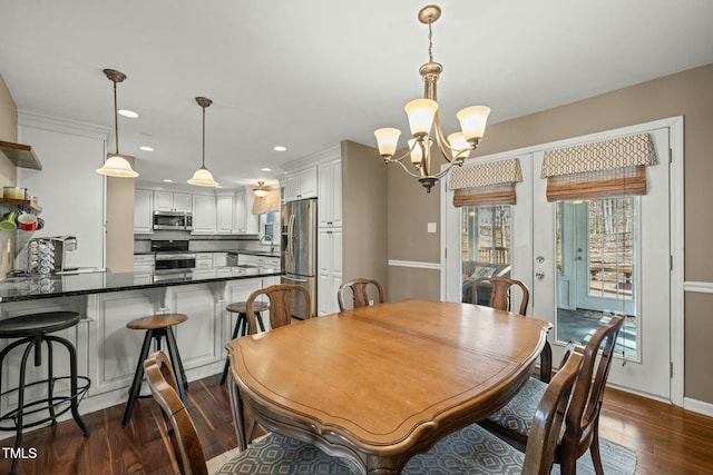 dining space with dark wood-type flooring, recessed lighting, baseboards, and an inviting chandelier