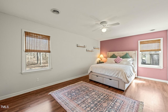 bedroom featuring baseboards, visible vents, ceiling fan, and wood finished floors